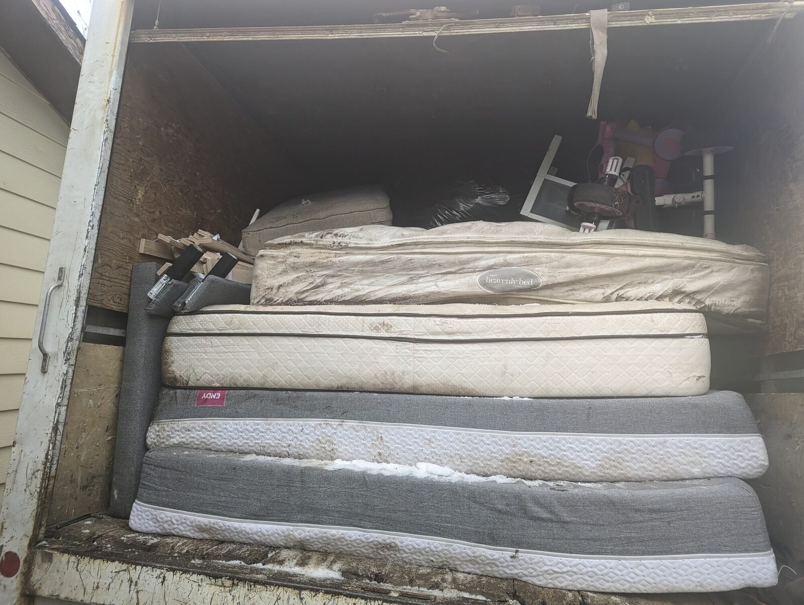 Old mattresses and box springs stacked and ready for haul-away during a Clearout Crew mattress removal in the Calgary area.