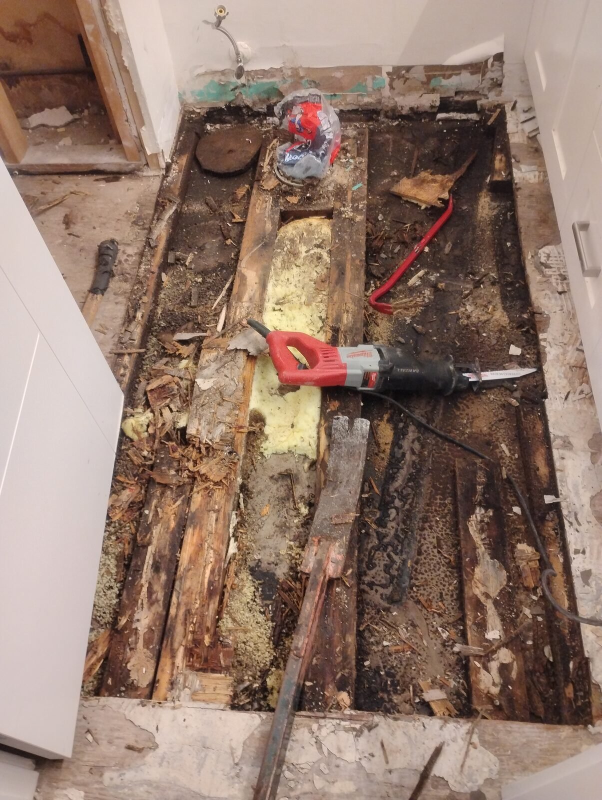 A bathroom floor being cut out with a reciprocating saw during a Clearout Crew strip-out in Calgary.