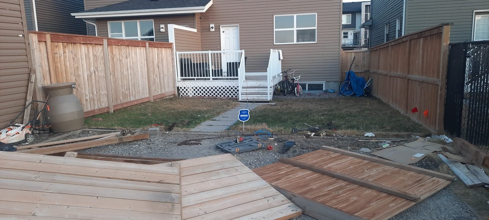 A backyard deck being removed, with large deck sections lifted out onto the lawn, on a Clearout Crew job in Calgary.